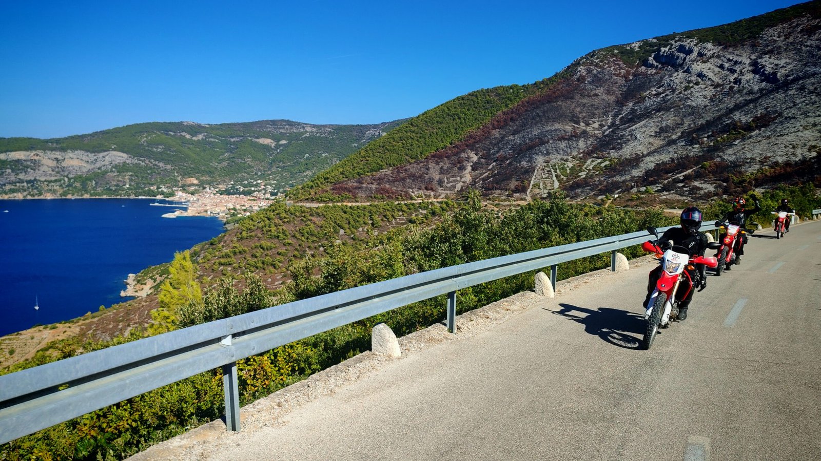 riders on dualsport motorcycles on vis island with a scenic backdrop